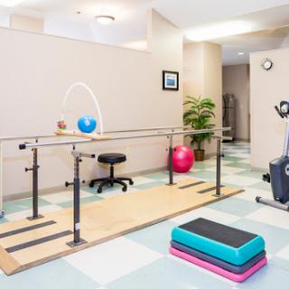 A well-equipped physical therapy room featuring a balance bar, exercise equipment, and a vibrant atmosphere.