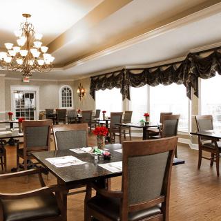 Elegant dining room with tables and chairs under a chandelier.
