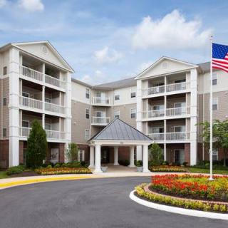 A multi-story residential building with balconies and a landscaped entrance, featuring an American flag.