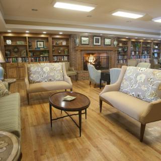 A cozy library with comfortable seating, bookshelves, and a fireplace.