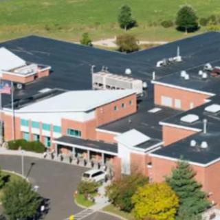 Aerial view of a school building surrounded by a parking lot and trees.