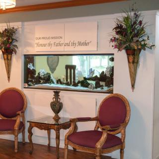 A cozy waiting area with two chairs, a small table, and a fish tank set into the wall, complemented by decorative floral arrangements.
