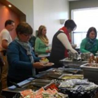 People serving themselves at a buffet table indoors.