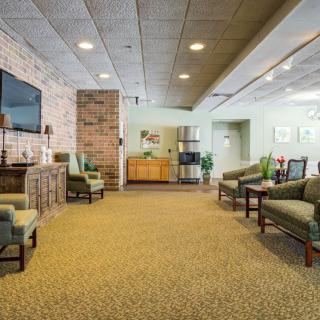 A spacious lobby or waiting room with comfortable seating and a television on the wall.