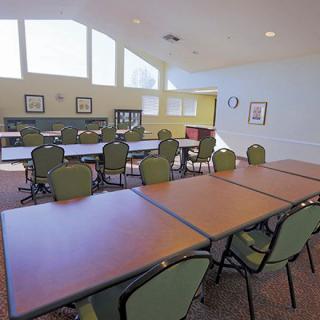 A spacious conference room set up with tables and chairs, illuminated by natural light through large windows.