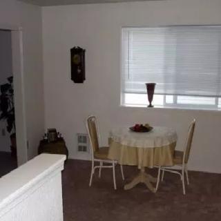 A simple dining area with a small table and two chairs near a window.