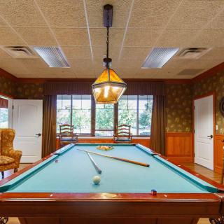A cozy billiards room featuring a pool table under warm lighting.