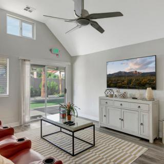 A modern living room with a ceiling fan, wall-mounted TV, and stylish decor.