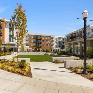 A modern residential apartment complex with landscaped outdoor areas and a clear blue sky.