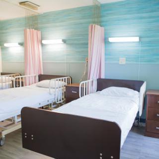 A serene hospital room with two neatly made beds, promoting a calm healing environment.