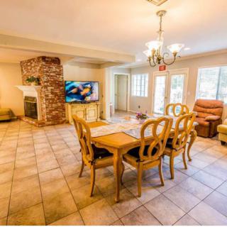 A cozy living and dining area featuring a brick fireplace, television, and classic furniture.