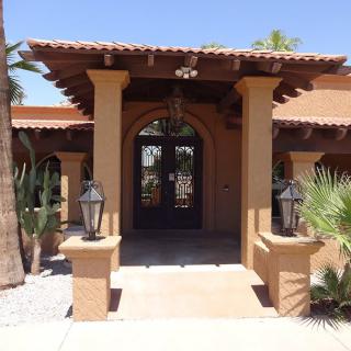 A Mediterranean-style house entrance with arched doorway and surrounding greenery.