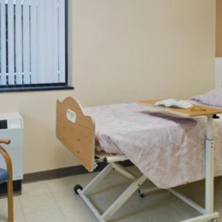 A hospital room with a single bed and medical equipment.