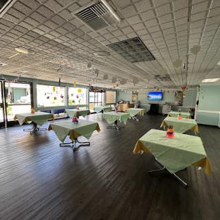 A spacious, empty restaurant setting with green tablecloths and a modern interior.