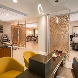 A modern salon interior featuring stylish chairs and a well-lit nail station.