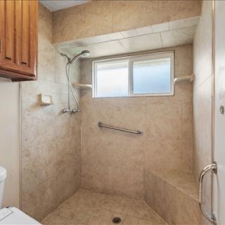 A spacious and accessible bathroom featuring a modern shower design with tiled walls.