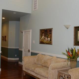 A cozy living room with a sofa, paintings on the wall, and a vase of flowers on a side table.