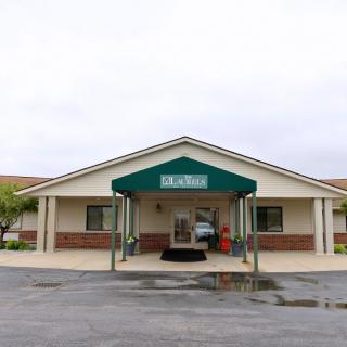 A building with a green awning over the entrance, located in a parking lot.