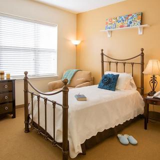 A cozy bedroom with a single bed, soft lighting, and warm decor.