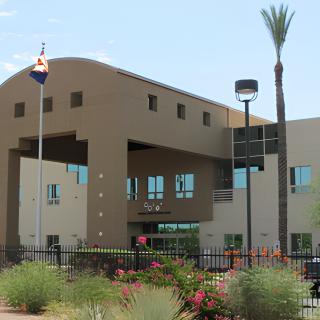 Modern building with desert landscaping and a flagpole in front.