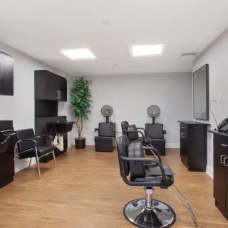 A modern hair salon interior featuring multiple styling stations and sleek black chairs.