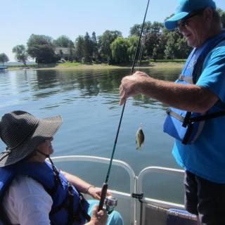 Two people fishing on a boat in a lake.