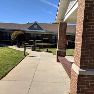 A well-maintained pathway leading to a brick building, surrounded by neatly trimmed lawns.