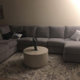 A cozy living room with a gray sectional sofa and a round coffee table.