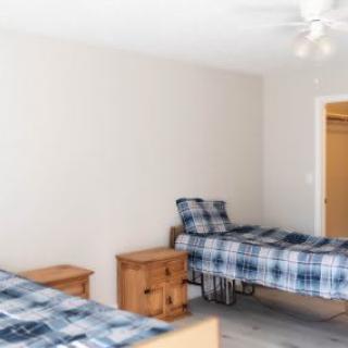 A minimalist bedroom with two twin beds featuring plaid bedding and wooden nightstands.
