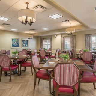 A well-decorated dining room with elegant chandeliers and neatly arranged tables and chairs.