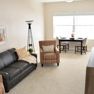 A cozy living room with a sofa, armchair, and dining area.