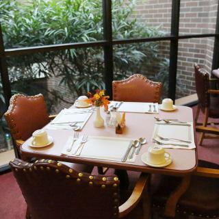 A cozy restaurant table set for four, overlooking a view of lush indoor plants through large windows.