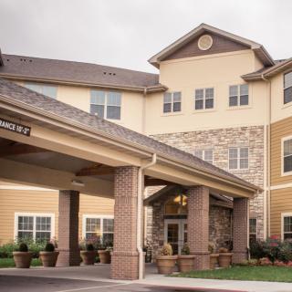 A residential building with a covered entrance and stonework facade.