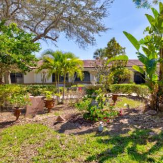 A beautifully landscaped garden with tropical plants and palm trees in front of a residential building.