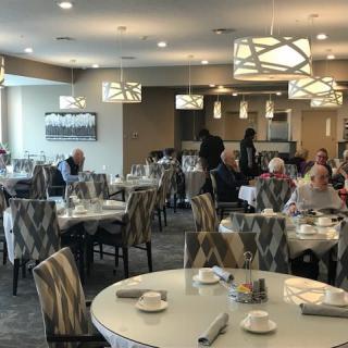A dining area with several tables and people seated, featuring modern lighting and decor.
