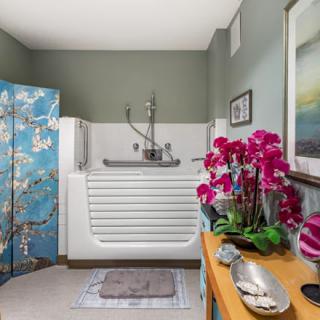 A modern bathroom featuring a walk-in bathtub, adorned with vibrant flowers and elegant decor.