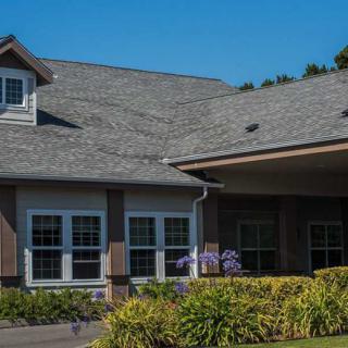 A suburban residential house with well-maintained landscaping under a clear blue sky.