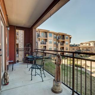A comfortable balcony with seating, offering a view of nearby apartment buildings.