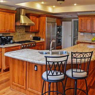 A modern kitchen with wood cabinets, granite countertops, and stainless steel appliances.