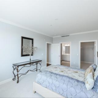 A bright and spacious minimalist bedroom featuring a comfortable bed and elegant furniture.