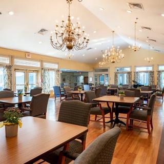A spacious and elegantly decorated dining room with multiple tables and chandeliers.