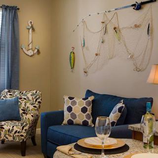 A cozy, nautical-themed living room with a blue sofa and decorative elements like an anchor and net on the wall.