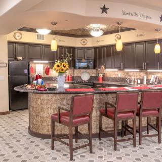 A warm and inviting kitchen interior with a curved counter, bar stools, and decorative pendant lights.