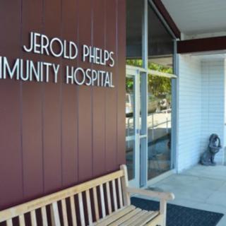 Entrance of Jerold Phelps Community Hospital with a bench and signage.