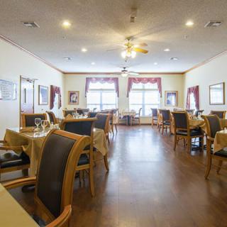 An empty dining room with neatly arranged tables and chairs, featuring large windows and elegant decor.