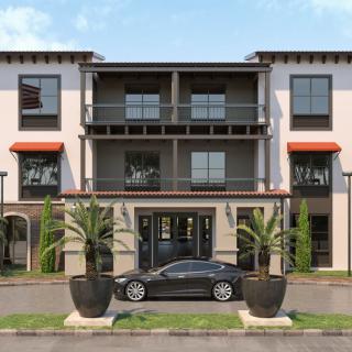 A modern three-story building with large windows and a dark car parked in front, flanked by two potted palm trees.