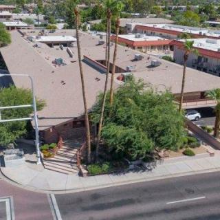 Aerial view of an urban building surrounded by palm trees at a road intersection.