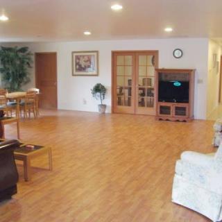 Spacious living room with wooden flooring, comfortable seating, and a television.