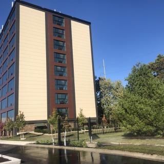 A tall building surrounded by trees under a clear blue sky.