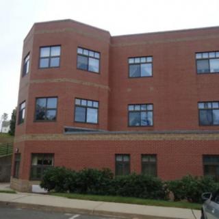 A view of a brick building with multiple windows in an urban setting.